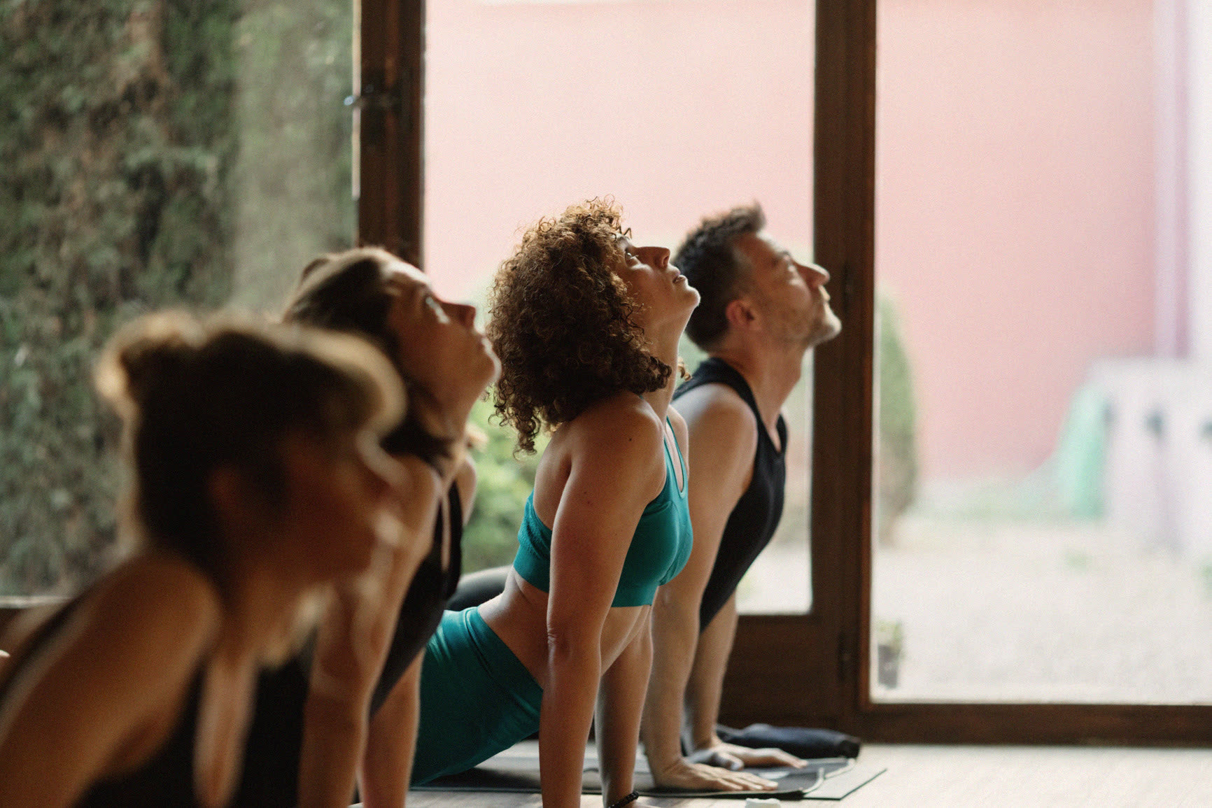 A row of people arching back together in a bright studio
