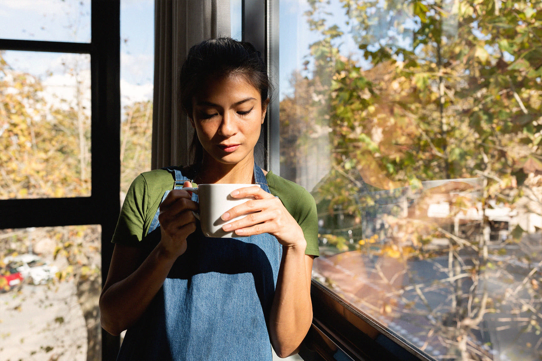A patient holding a warm drink by a sunlit window