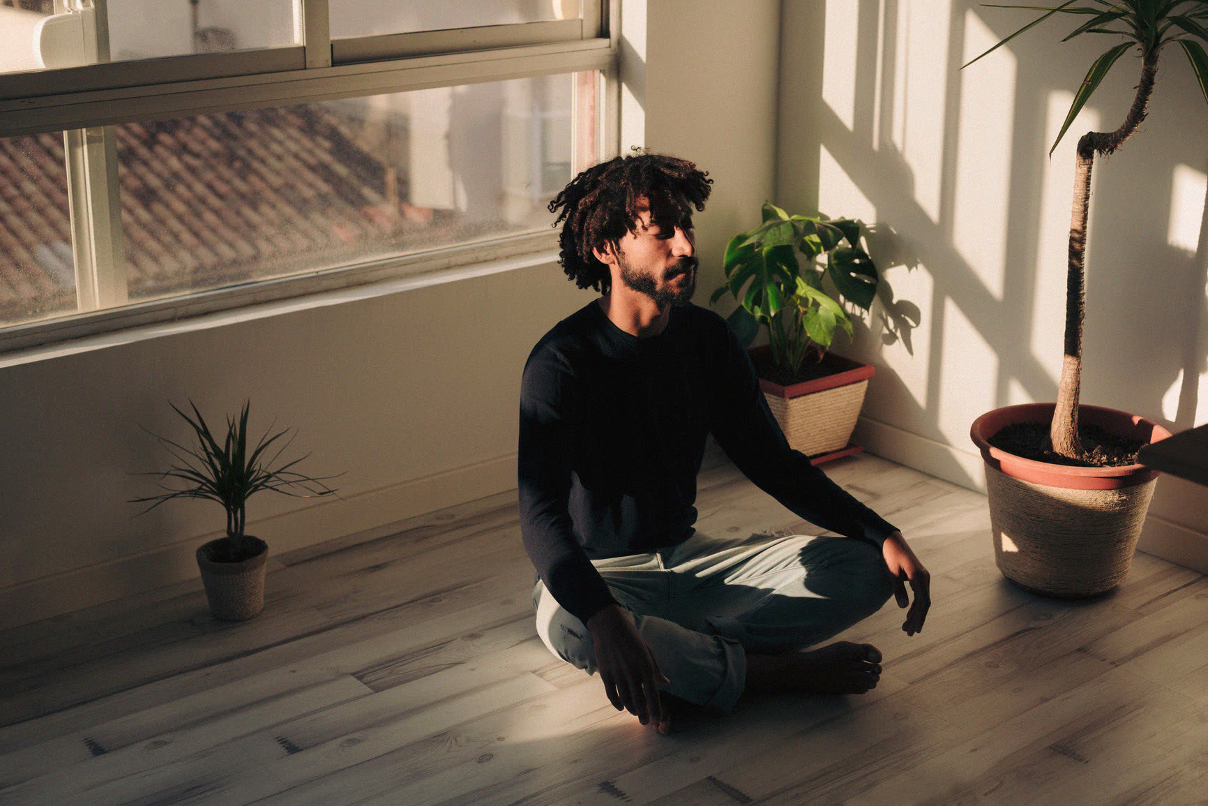 A patient meditating on the floor of a sunlit room